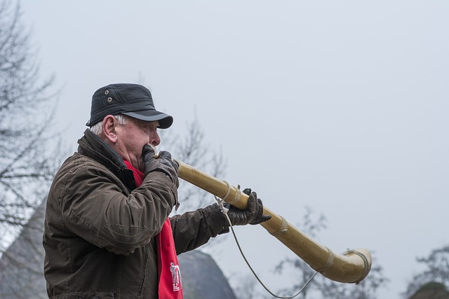 A modern old man playing a long blow horn.