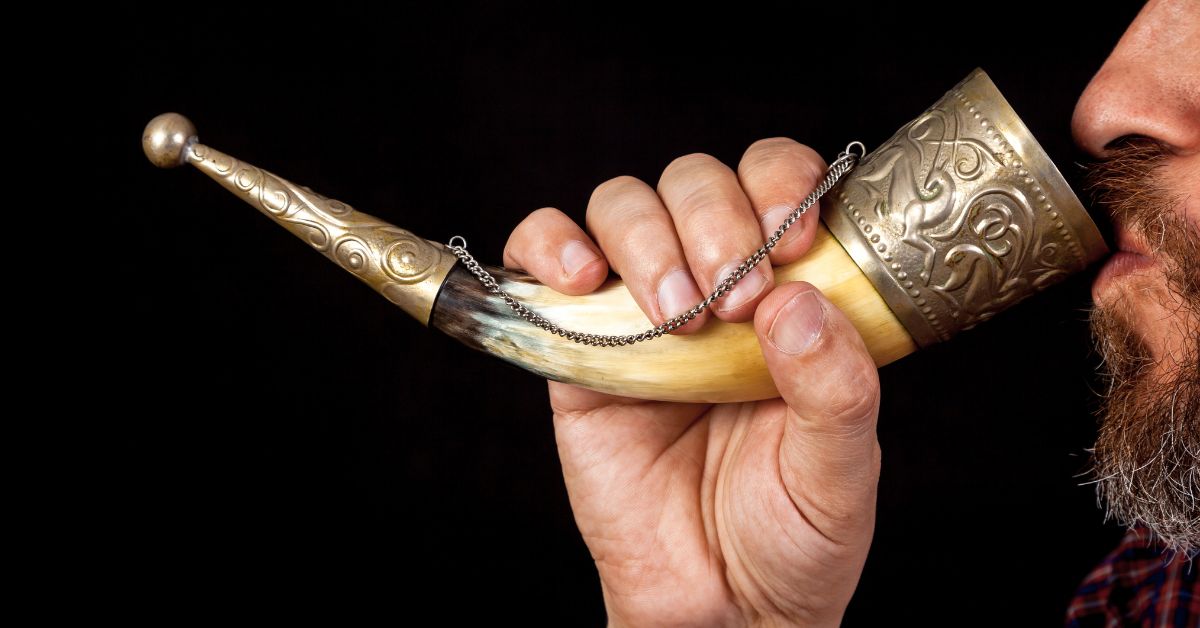 A bearded man properlu using a drinking horn.