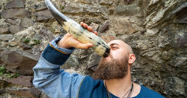 A man using a drinking horn in the nature.