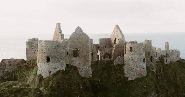 An old medieval castle sitting in an ocean coast.