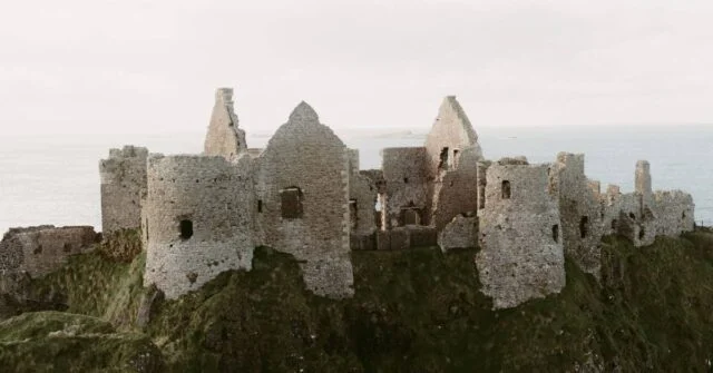 An old medieval castle sitting in an ocean coast.