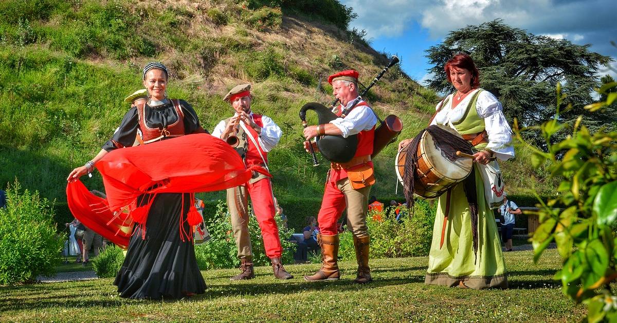 A man dancing while 3 people plays instrument in a medieval festival.