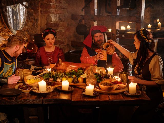 Medieval people having dinner in an ancient looking kitchen.