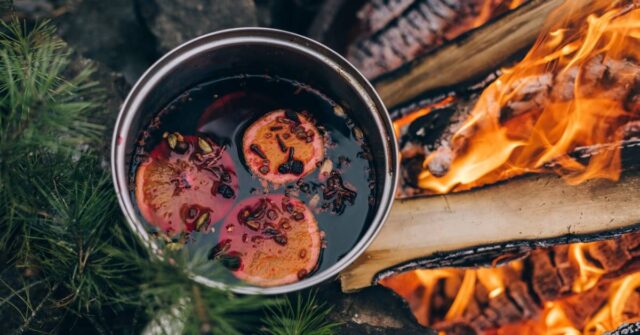 A mulled wine being cooked outside using firewoods.
