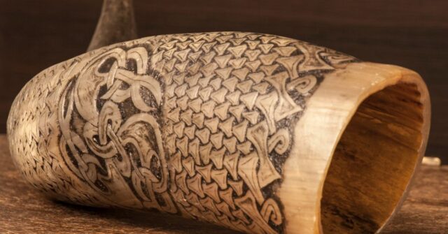 An old carved drinking horn in a wooden table.