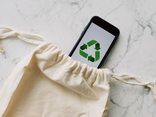 An eco friendly bag with a phone that display a recycling logo.