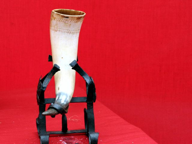 An animnal drinking horn displayed on a custom stand.