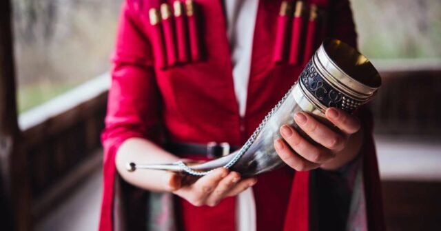 A man wearing traditional clothing and holding a drinking horn.