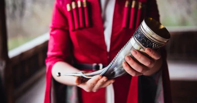 A man wearing traditional clothing and holding a drinking horn.