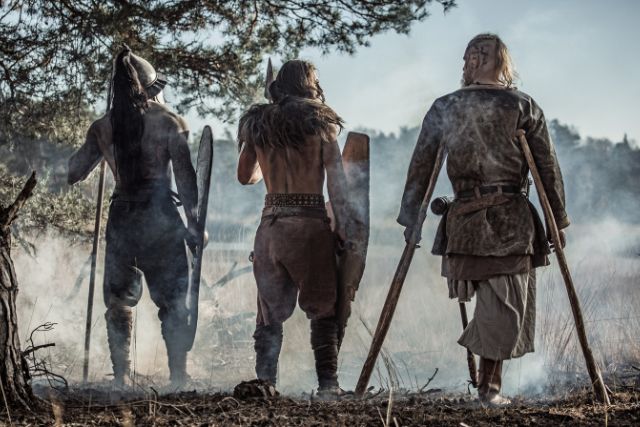 Three viking warriors standing in a forest.