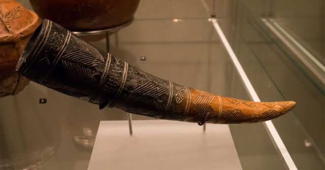 Close up of an old drinking horn from Cyprus with intricate carvings on it.