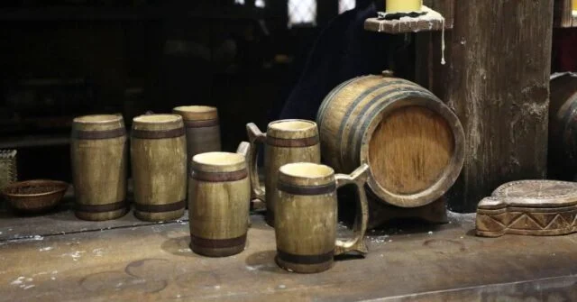 Old style medieval bar with wooden barrel and wooden beer mugs.
